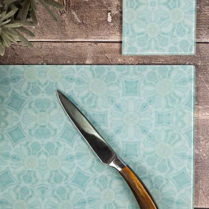 Patterned glass cutting board with a knife on a wooden surface